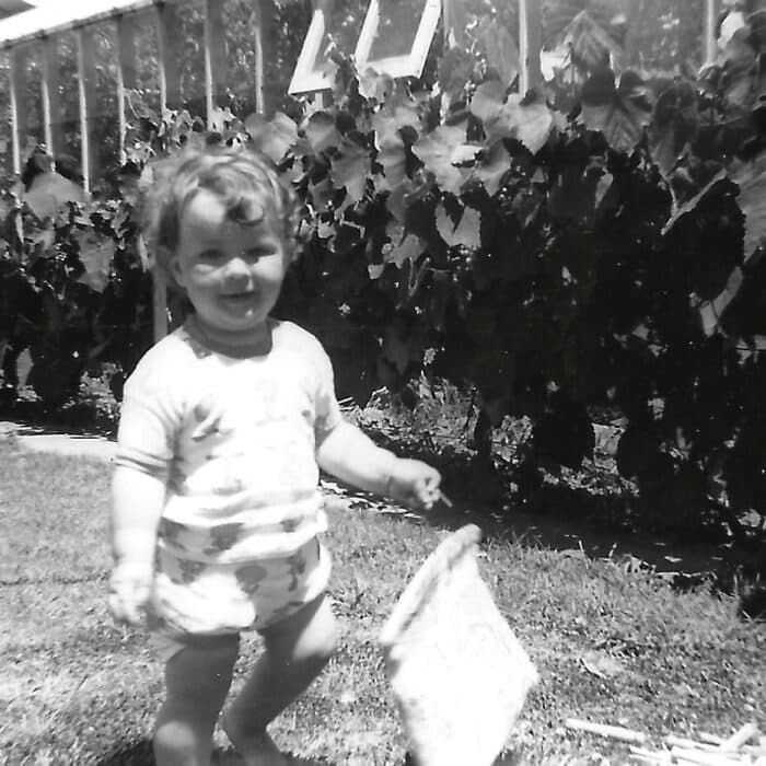 Black and white image of a child walking on a lawn
