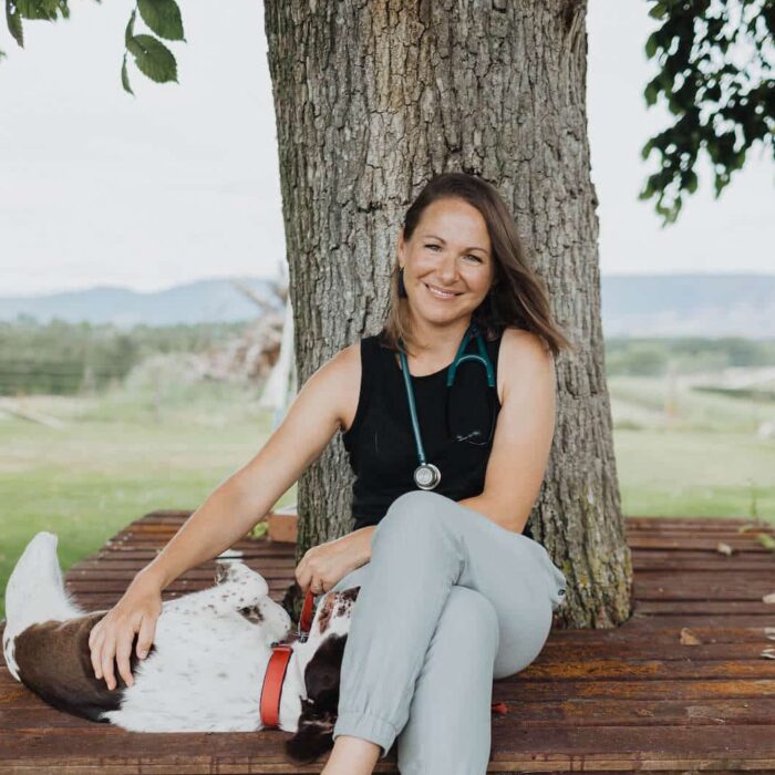 Woman sits in front of a tree with a dog