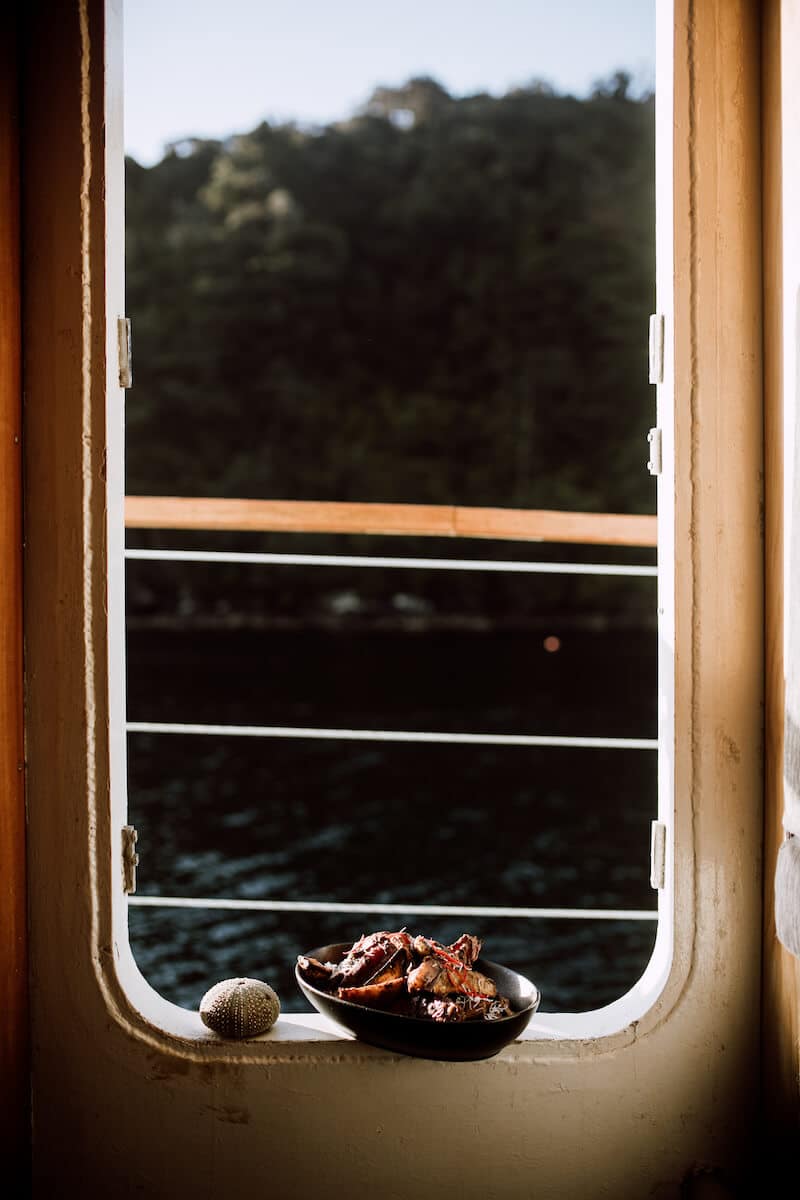 The light streaming through one of the doors on the MV Flightless, illuminating a kina sea urchin and a lunch prepared – appropriately – in Luncheon Cove.