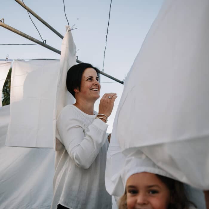 Woman hanging out washing with one of her children playing in a sheet