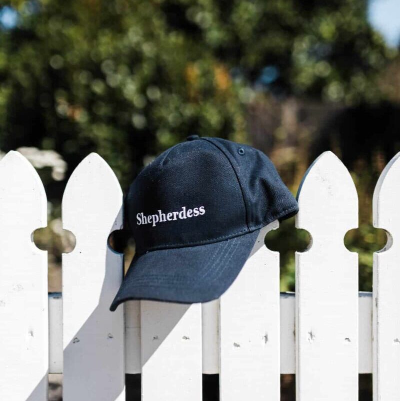 Shepherdess embroidered cap hangs on a picket fence