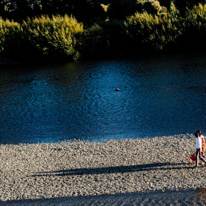 A couple walks beside a river